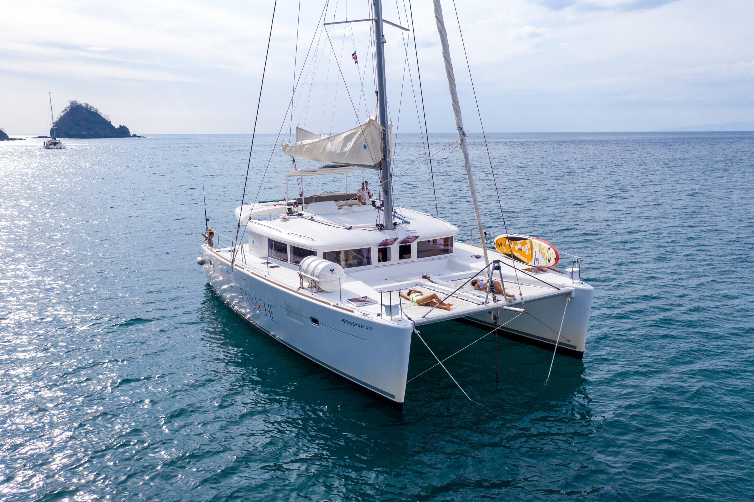 Luxury catamaran anchored in calm waters near a rocky coastline, ideal for boat trips in Costa Rica.